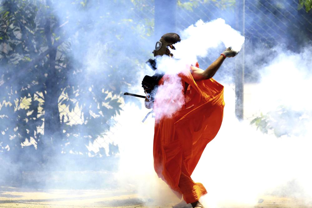 A man throws back a tear gas canister after it was fired by police to disperse protesters in Colombo, Sri Lanka, Saturday, July 9. (AP Photo)